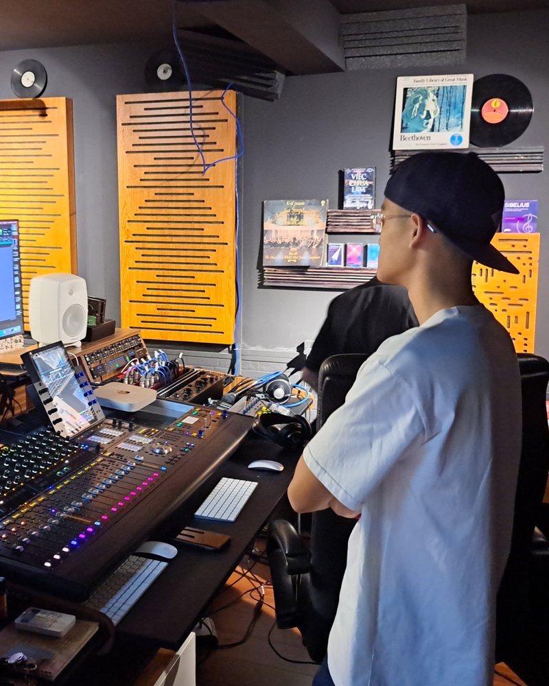 Bach in a recording studio control room, watching a session on screen