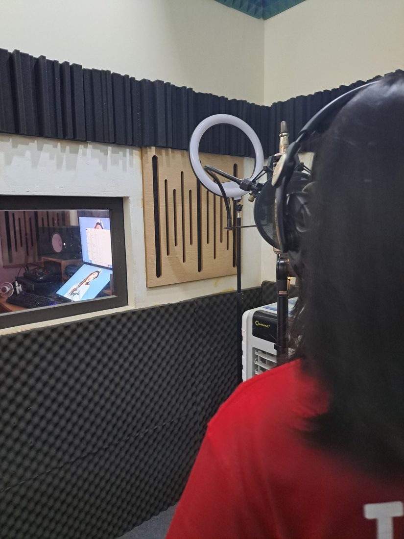 Minh Anh in the booth, looking through to the control room.